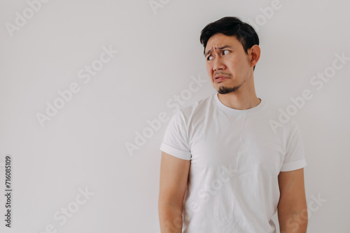 Funny bored and disappointed face Asian man in white t-shirt isolated on white wall.