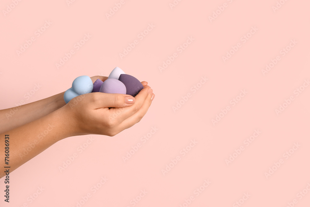 Female hands with different makeup sponges on pink background - obrazy, fototapety, plakaty 