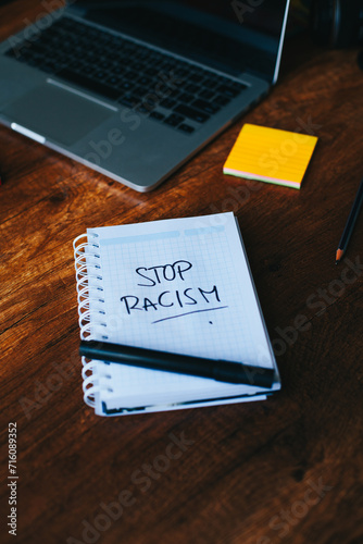 photograph of notebook with phrase "stop racism" on a table. 