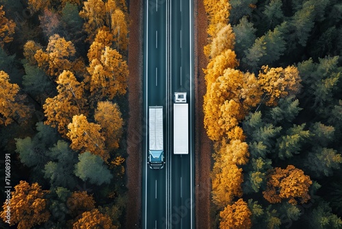 Drone captures autumnal forest road two trucks viewed from above photo