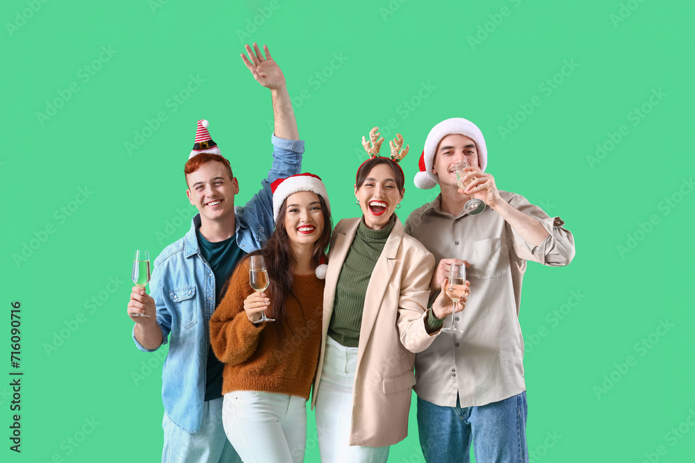 Obraz premium Group of friends with champagne on green background. New Year celebration