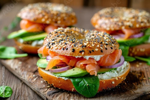 Lox everything bagel with smoked salmon spinach red onions avocado and cream cheese on rustic wood table with blurry background
