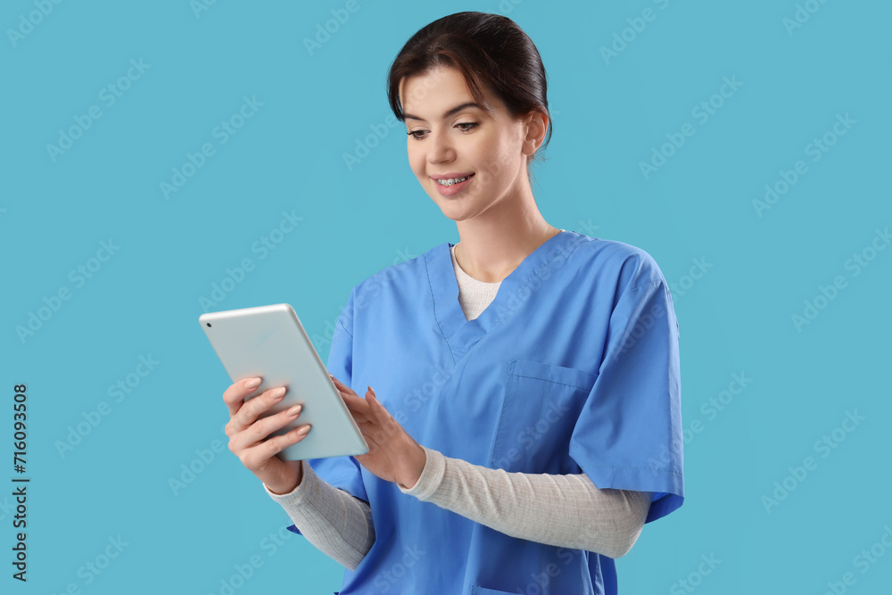 Female medical intern using tablet computer on blue background Female medical intern using tablet computer on blue background