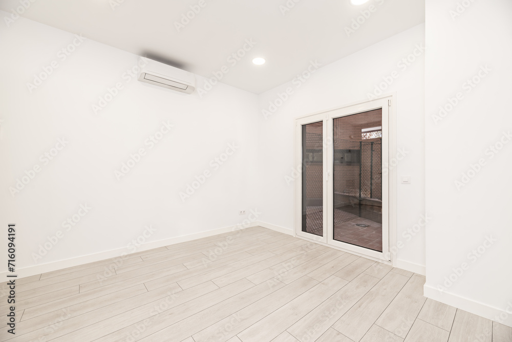 An empty white room in a loft-style home with an aluminum and glass