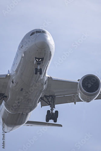 View of the underside of the fuselage of a passenger plane at low altitude near the runway