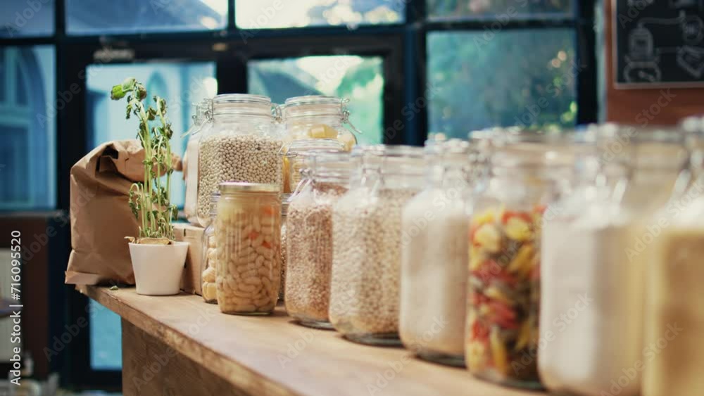 Local zero waste grocery store with bulk products in jars, empty supermarket isles. Additives free pasta, sauces and spices stored in recyclable glass containers on display. Handheld shot. Local zero waste grocery store with bulk products in jars, empty supermarket isles. Additives free pasta, sauces and spices stored in recyclable glass containers on display. Handheld shot.