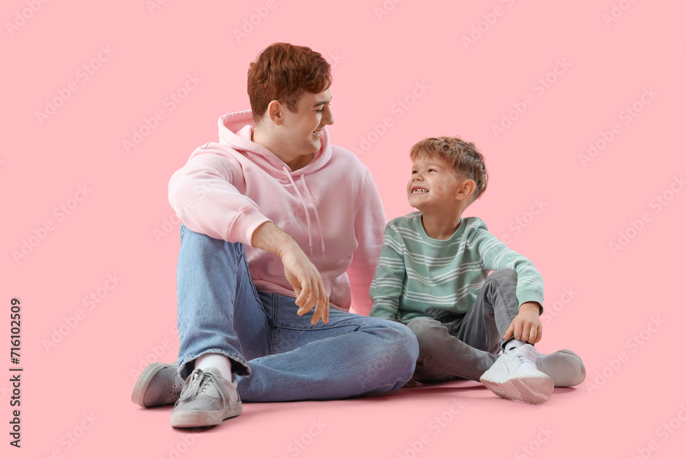Little boy with his father sitting on pink background Little boy with his father sitting on pink background