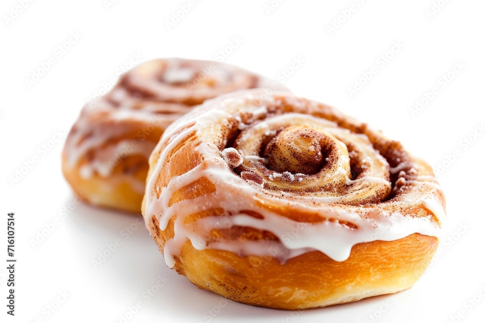 Two cinnamon rolls with icing on a white surface Two cinnamon rolls with icing on a white surface