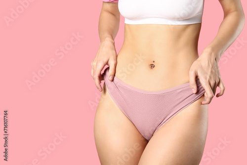 Young woman in panties on pink background photo