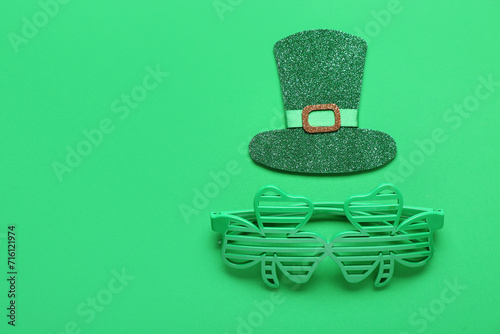 Paper leprechaun's hat and plastic eyeglasses on green background. St. Patrick's Day celebration