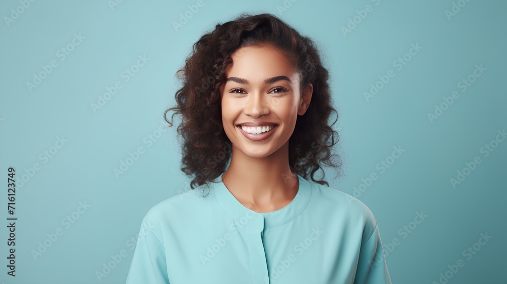 Fototapeta premium Portrait of happy smiling young african american woman with curly hair over blue background