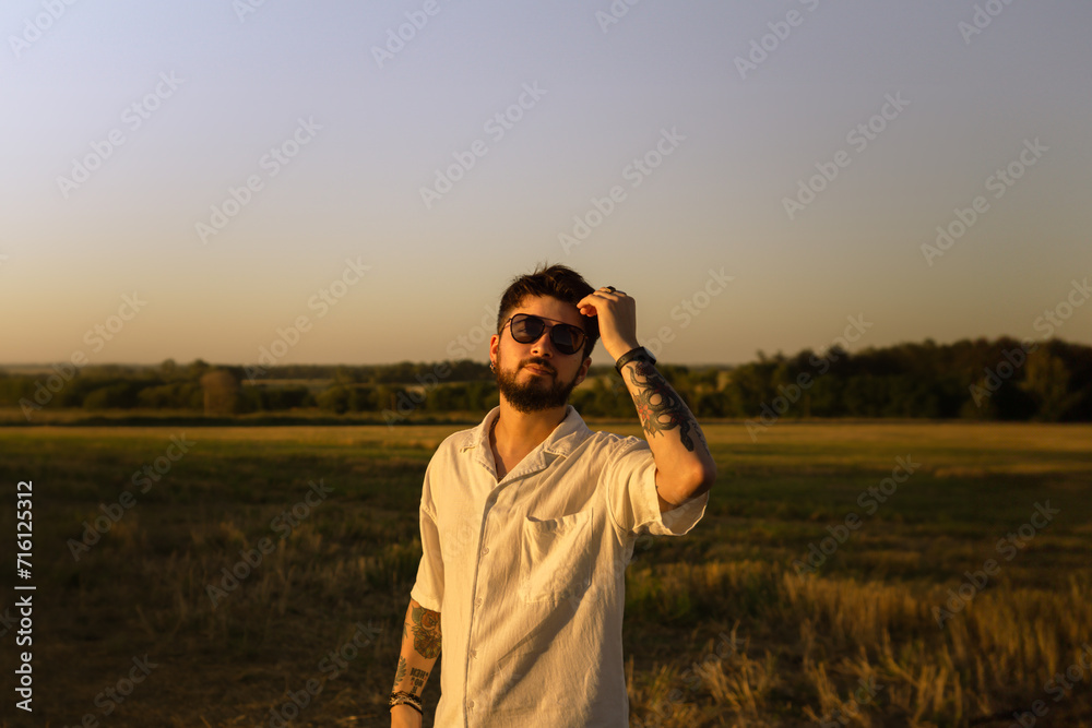 Fototapeta premium handsome young man in a field at sunset