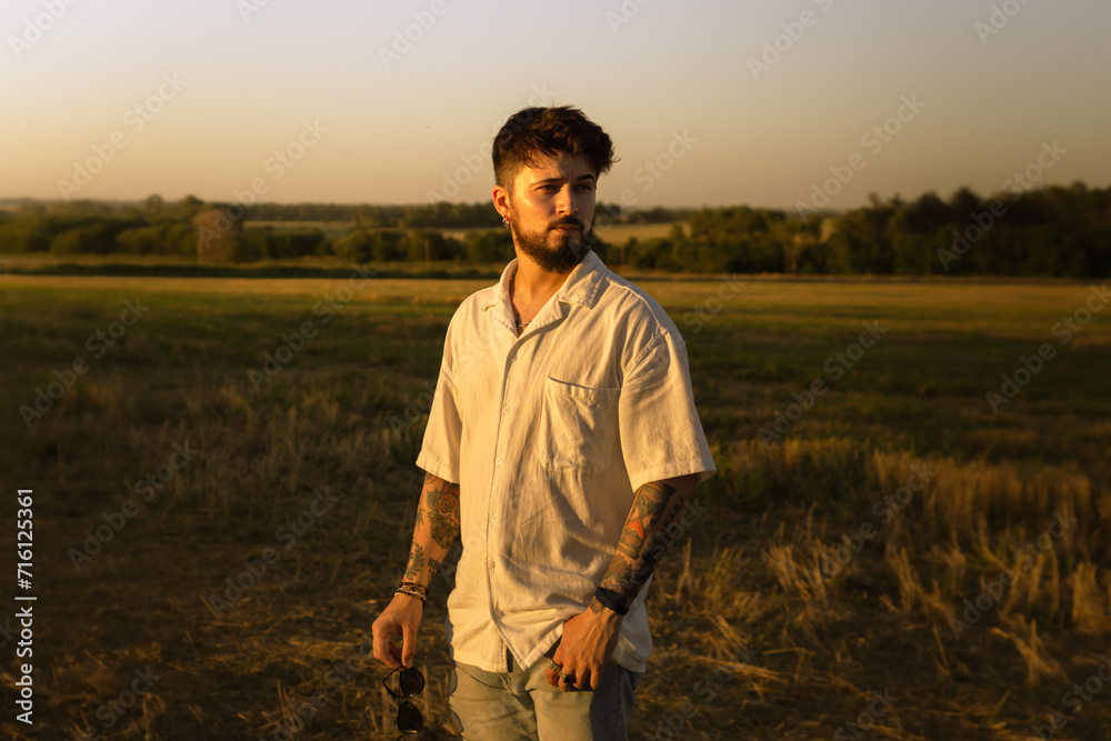 handsome young man in a field at sunset handsome young man in a field at sunset