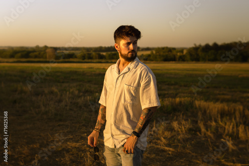 handsome young man in a field at sunset