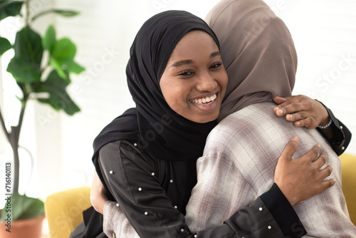 Multiracial Muslim women in traditional hijab showing traditional Muslim greeting hug, Salam, As-salamu alaykum, Peace be upon you photo