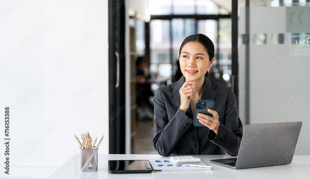 Thinking about how to take the business to technological heights. Young businesswoman using mobile phone while working in her office. Thinking about how to take the business to technological heights. Young businesswoman using mobile phone while working in her office.