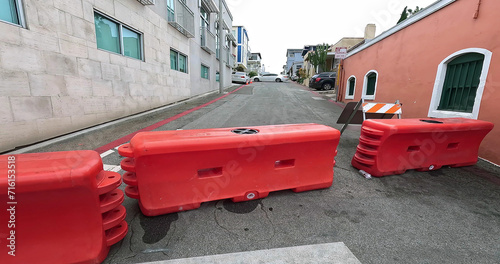 Row of red road construction plastic water barrier barricades and roadblocks filled by water on the street driveway in Los Angeles