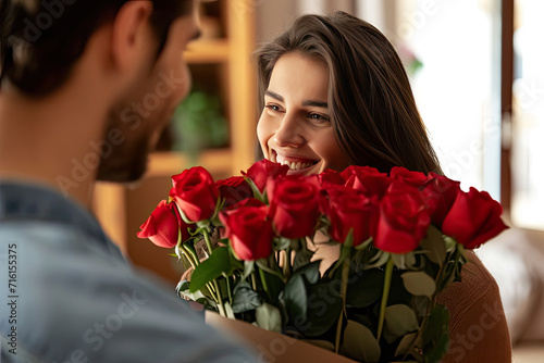 closeup a young man surprising his wife with a bunch of roses at home