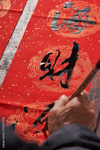 An old calligrapher writes couplets during the Chinese Year of the Dragon.
Translation: The auspicious energy brings auspiciousness and the wealth is abundant. photo