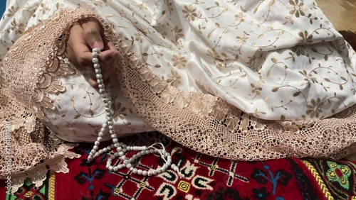 Muslim woman doing dhikr using prayer beads photo
