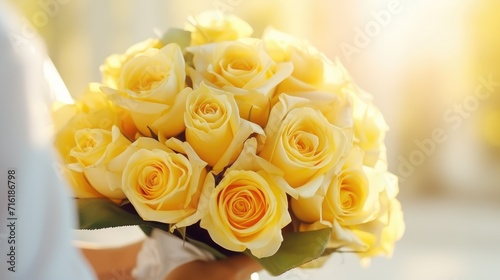 A bouquet of yellow roses in women s hands for congratulations on Mother s Day  Valentine s Day  Women s Day. Blurred background.