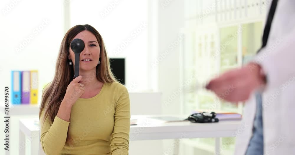 Adult vision check by ophthalmologist and woman closes one Adult vision check by ophthalmologist and woman closes one