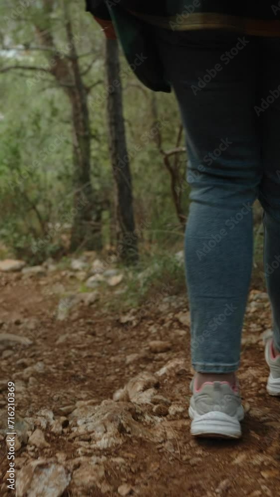 Vertical video. Following Behind a Sporty Woman Descending from the Mountain on a Rocky Steep Path with a Backpack on her Back. Vertical video. Following Behind a Sporty Woman Descending from the Mountain on a Rocky Steep Path with a Backpack on her Back.
