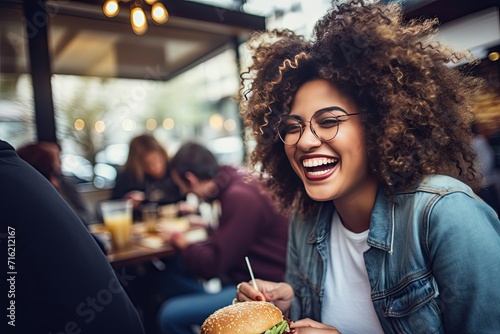 Joyful Curly-Haired Woman Enjoying a Burger at a Cafe