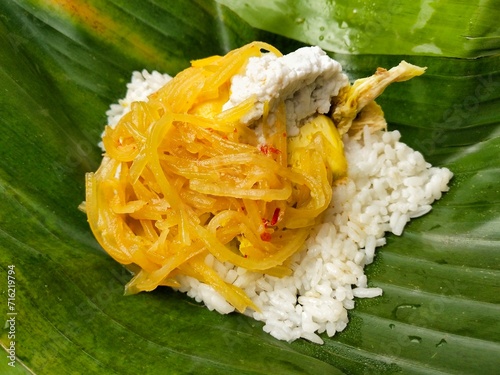 Nasi liwet, a typical dish of Surakarta City, Indonesia, is savory rice. It comes with shredded chicken, half a boiled egg, egg pudding, chayote curry, and areh or thick coconut milk photo
