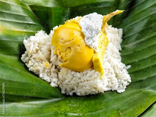 Nasi liwet, a typical dish of Surakarta City, Indonesia, is savory rice prepared using coconut milk. It comes with shredded chicken, half a boiled egg, egg pudding, and areh or thick coconut milk photo