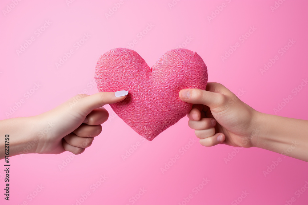 Two hands holding pink heart on pink background. Perfect for Valentine's Day or expressing love and affection in any context Two hands holding pink heart on pink background. Perfect for Valentine's Day or expressing love and affection in any context