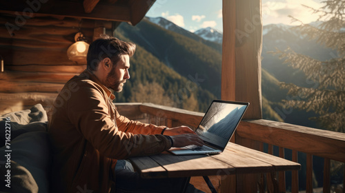 Man collaborating with colleagues on a laptop from a mountain cabin, experiencing the joys of remote work