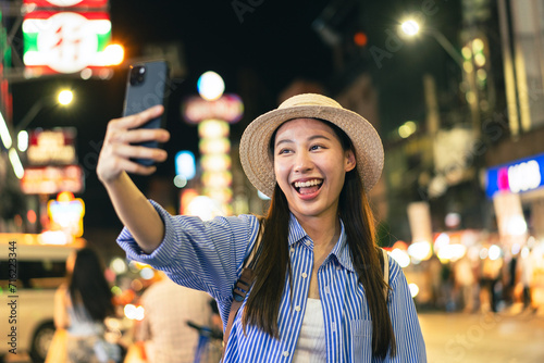 Traveler asian young woman using smart phone camera to take photo, selfie or video call at china town in Bangkok. Backpacker travel on holiday trip or vacation concept