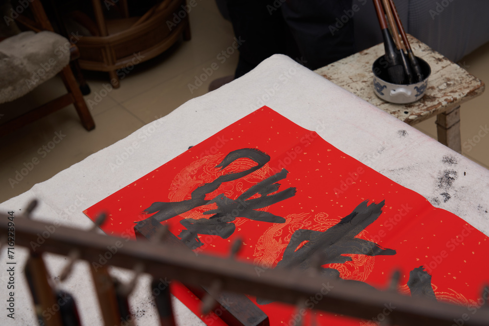 Obraz premium An old calligrapher writes couplets during the Chinese Year of the Dragon. Translation: May you welcome the Spring and good luck in the Year of the Dragon.