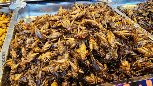 Exotic Thai street food Fried insects in a market showcase, Creating a delicious and healthy snack option. The bugs are often deep fried mixed with pandan, salted before being served. photo