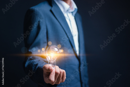 Business creativity and inspiration concept. Businessman holding bright light bulb for motivation for success and thinking of ideas.