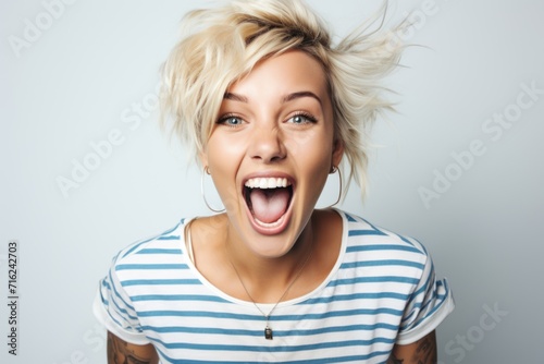 A funny Gen Z blonde girl wearing a striped t-shirt with short blond hair tattoos