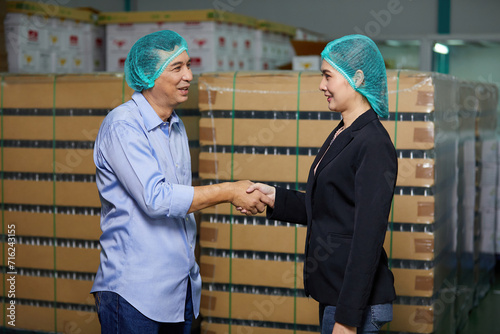 businessman meeting and shaking hands with businesswoman in the beverage factory