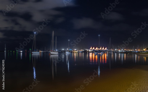 Lights and reflections across the Broadwater at night with yachts and the marina with its iconic sail shaped roof on the Gold Coast , a popular tourist destination in Queensland, Australia. photo