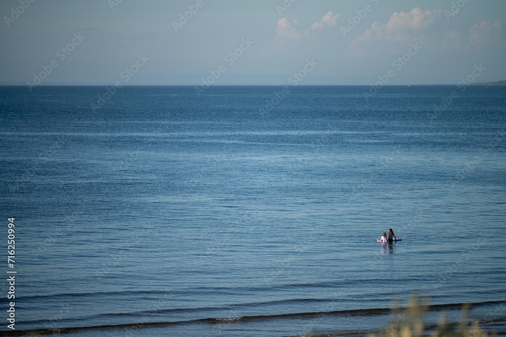 sandy beach with familys swimming at dusk on phillip island australia on a hot summer evening