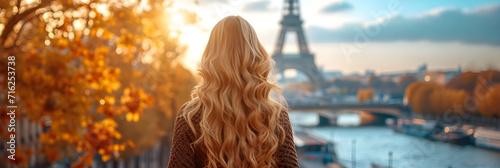 A beautiful slim girl with long blond hair standing in front of the Eiffel Tower in Paris. photo