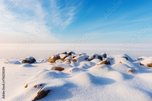 Beautiful winter landscape with stones on foreground and frozen lake © Vitaliy