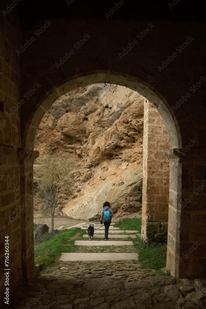 Young woman walking with dog and sightseeing in the medieval hermitage of Tobera
