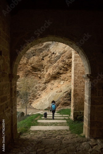 Young woman walking with dog and sightseeing in the medieval hermitage of Tobera © pintxoman