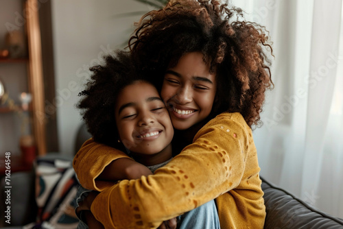 Mother's Day family holiday unconditional love concept. Adorable child hugging and embracing mom, Portrait of happy African American mommy and her child kid hugging each other at home