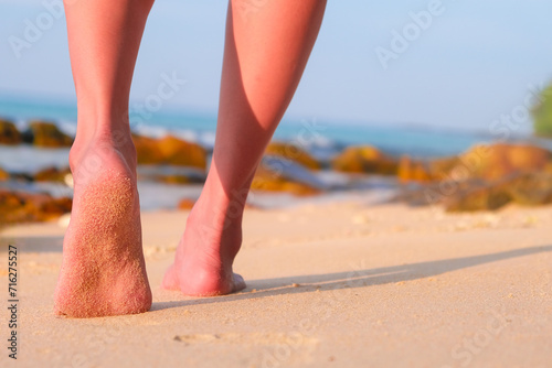 woman walking to sea and beach on a beautiful island Ocean foam wrapped around a girl's leg. Walking in the early morning sunshine to get natural vitamin D	
