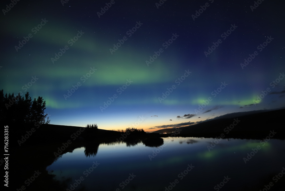 Aurora Borealis reflected in the water surface of a pond in Iceland Aurora Borealis reflected in the water surface of a pond in Iceland