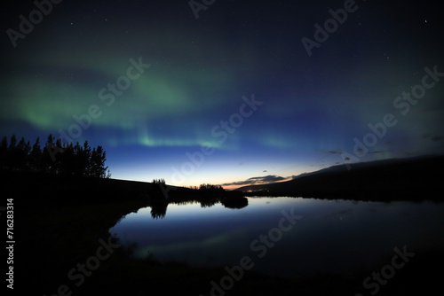 Aurora Borealis reflected in the water surface of a pond in Iceland