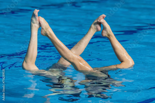Fluid grace and synchronized beauty of a female duet, dancing in perfect harmony in the mesmerizing aquatic ballet of synchronized swimming
