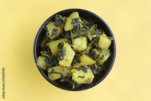 Aloo Palak sabzi, Spinach Potatoes dry curry served in a black bowl, Indian food photo